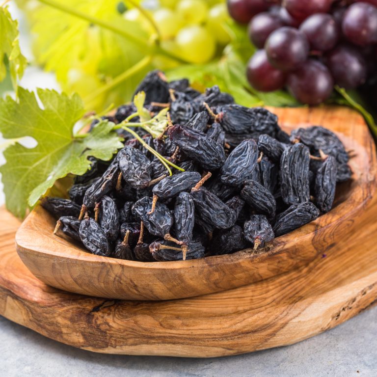 Black raisins  in bowl on stone  background, table top view. Dried fruit, healthy snack food